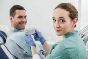 selective focus of cheerful dentist holding color palette near patient