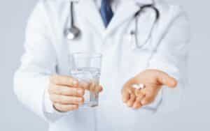 doctor holding a glass of water and antibiotics