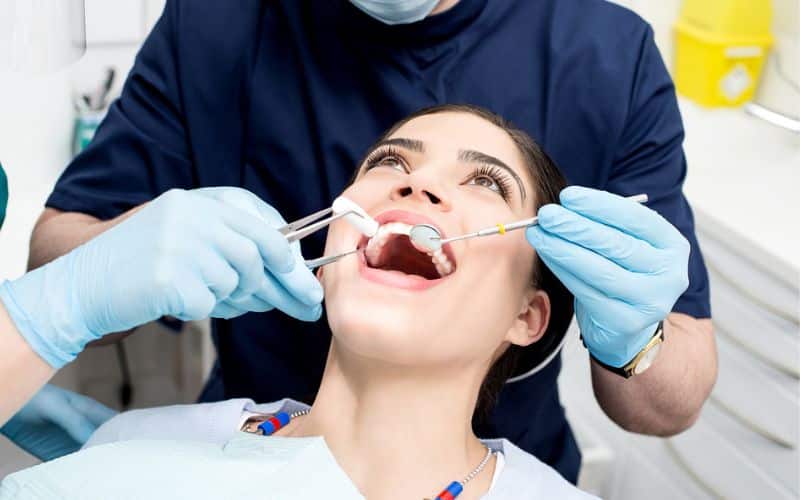 A woman is undergoing routine dental checkups and cleanings to maintain her veneers