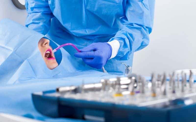 dentist wearing blue uniform performing bone gum graft treatment