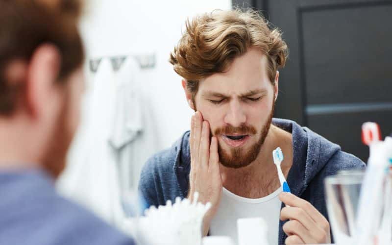 A man holding a toothbrush with a sensitive tooth