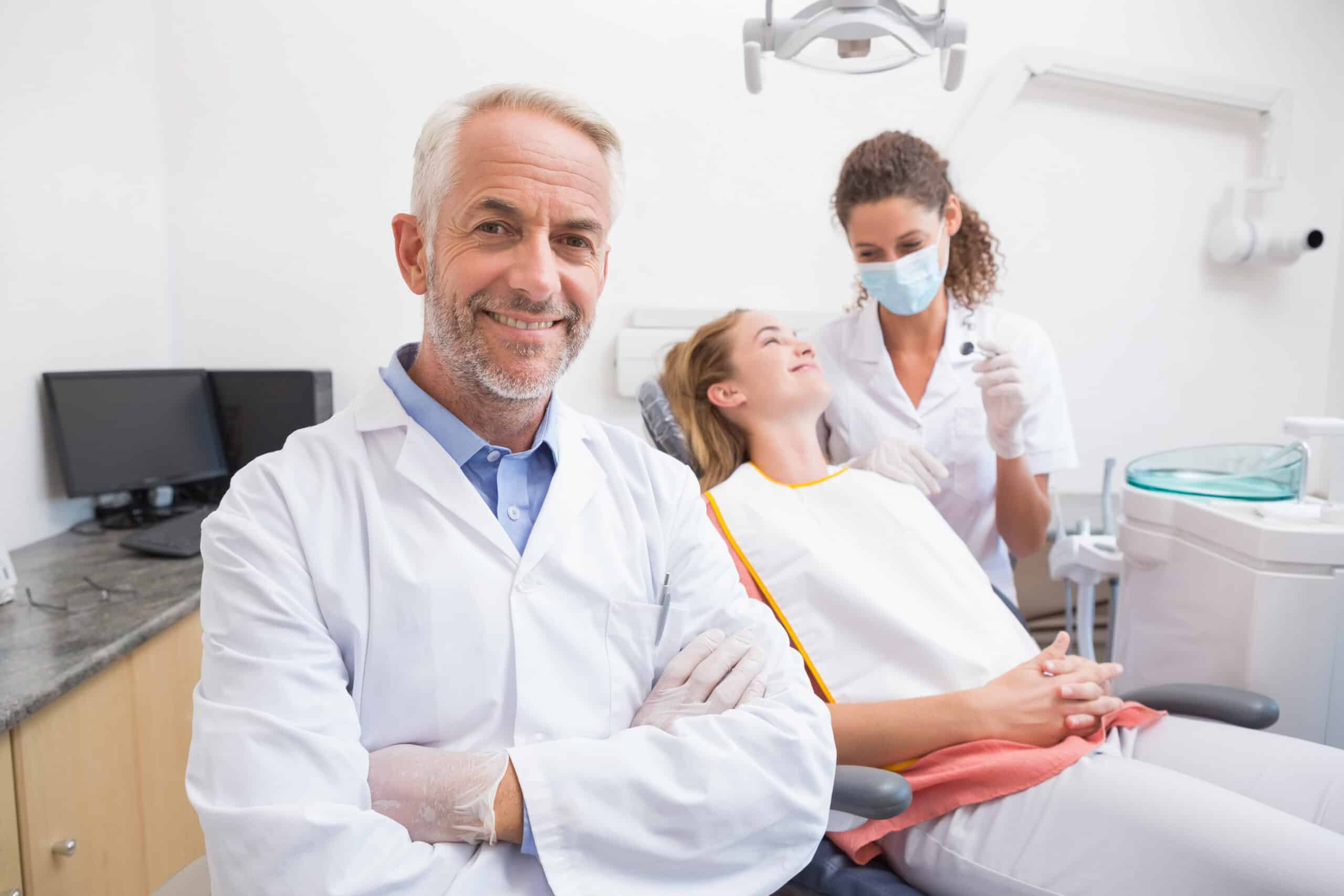 Dentist, assistant, and patient smiles at dental clinic