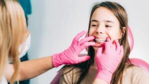 Orthodontist adjusting girl’s dental braces