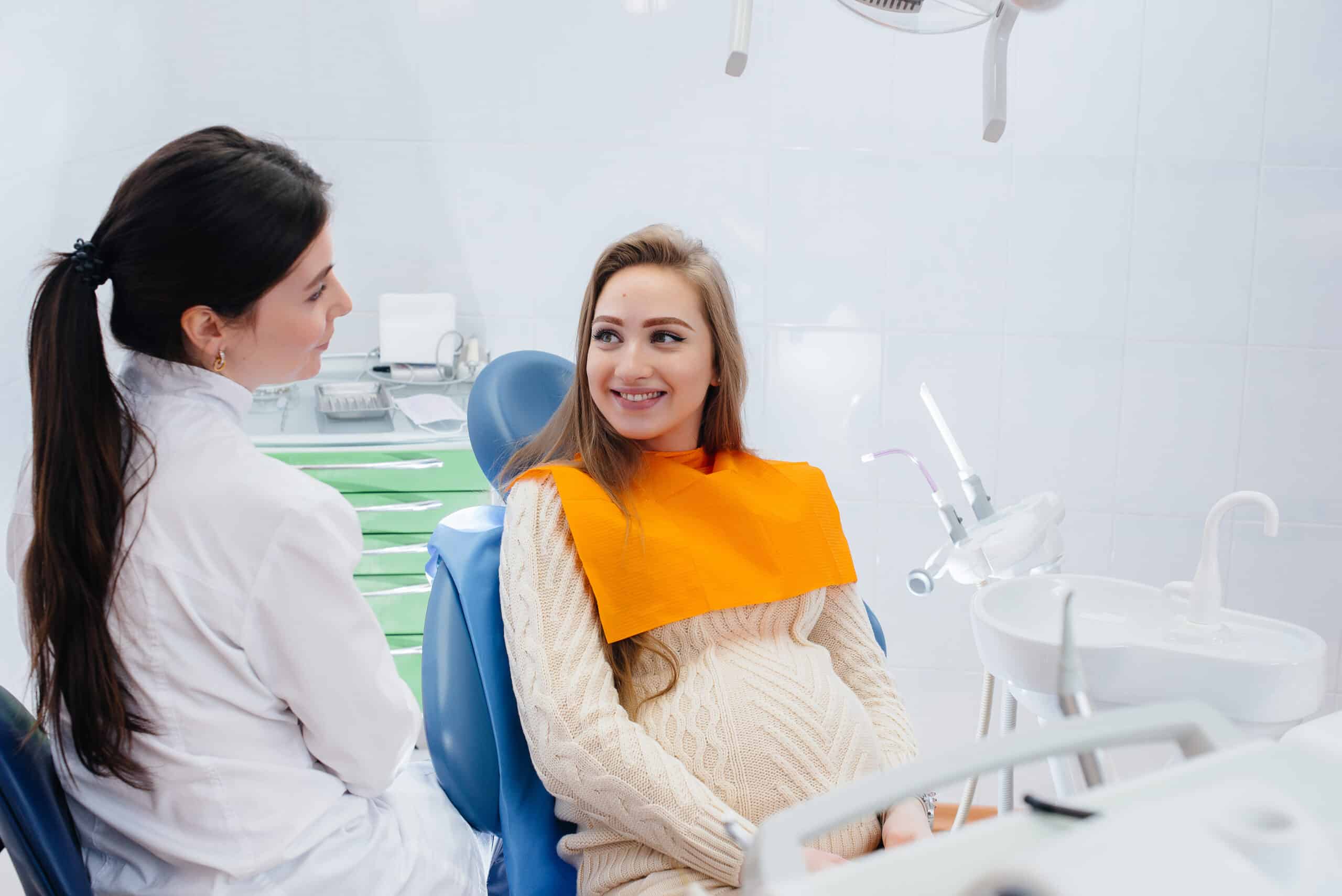 A professional dentist treats and examines the oral cavity of a pregnant girl in a modern dental office