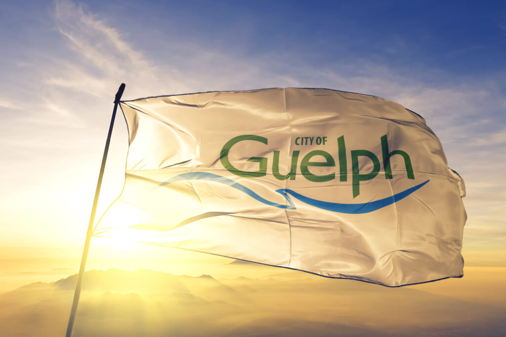 Guelph of Ontario of Canada flag textile cloth fabric waving on the top sunrise mist fog